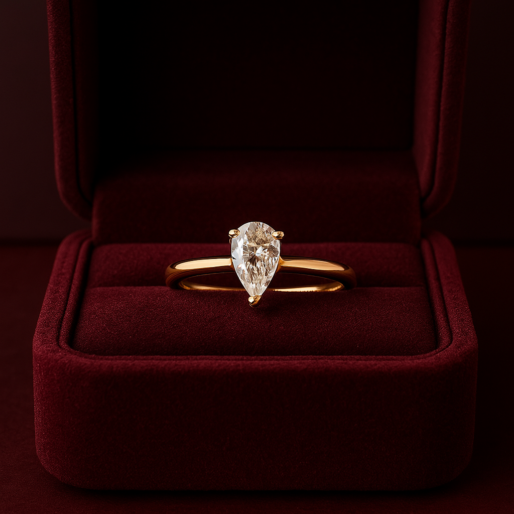 Elegant Onyx Oslo 1 karat Pæreslipt Exo Diamantring i 18K gull, vist i en luksuriøs rød fløyelseske, symboliserer ekte kjærlighet. Perfekt for forlovelser.