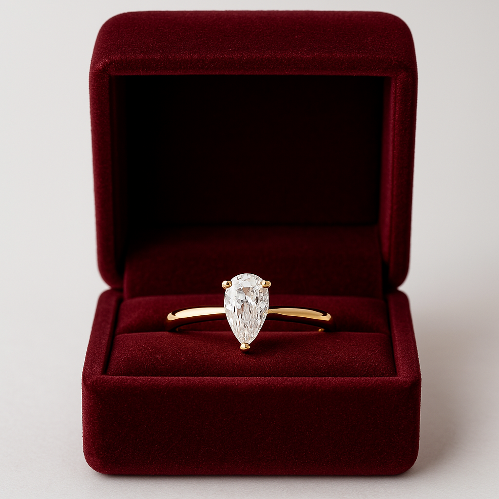 Onyx Oslo Päronslipad Exo Diamantring i en röd sammetsask, med en 1 karat VVS1 päronslipad sten i 18K guld, perfekt för förlovningar.